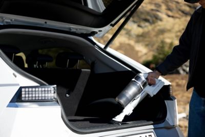 En mann støvsuger bagasjerommet i en IONIQ 5. Foto.