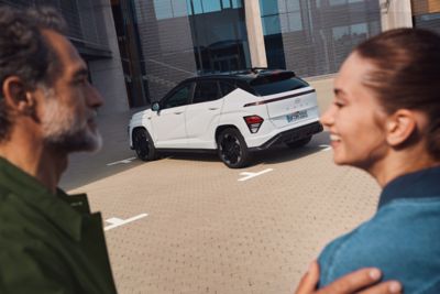 En dame lener seg mot en KONA Electric. Foto.