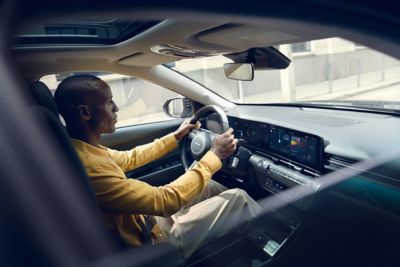 Interior view in the new Hyundai Kona Hybrid compact SUV showing the passenger using Bluelink.