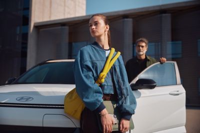 En dame lener seg mot en KONA Electric. Foto.