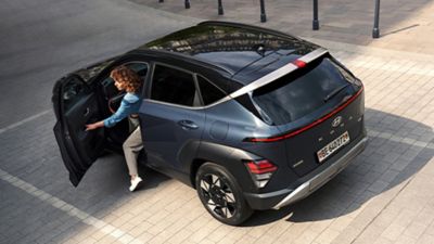A woman getting out of the all-new Hyundai KONA in black through the driver's side. 