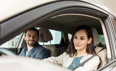 Kobieta siedzi za kierownicą samochodu Hyundai i obok siedzi mężczyzna na miejscu pasażera.