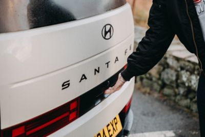 A woman carrying a basket walking toward the Hyundai SANTA FE Hybrid.