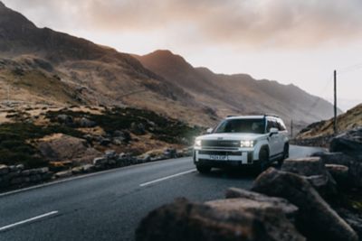 Two people leaned against the Hyundai Santa Fe watching the sunset from a mountain. 