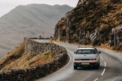 A woman leaning on the hood of the Hyundai Santa Fe with its H shaped LED headlamps visible