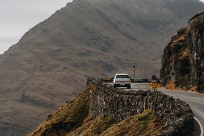 The Hyundai Santa Fe driving down a road with trees and hills in the background.