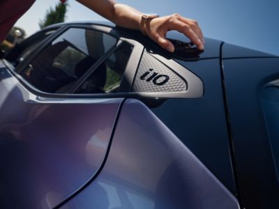 Un homme a sa main posé sur la nouvelle Hyundai i10 à côté le logo i10.