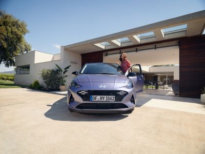 Een vrouw stapt in aan de bestuurderskant van de nieuwe Hyundai i10. 