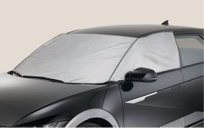 Ein Hyundai IONIQ 5 mit aufgelegtem Eis- und Sonnenschutz auf den vorderen Scheiben. 