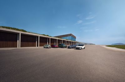 Five Hyundai EV cars parked side by side in front of a modern building, under a clear blue sky.