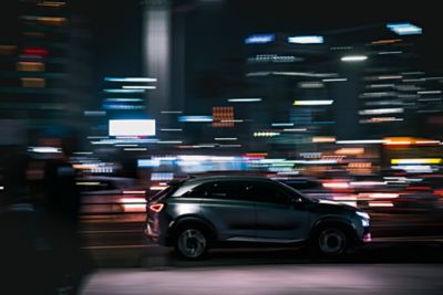 Hyundai SUV driving through a city scape at night