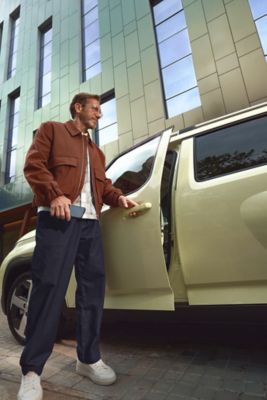 Muž otvára dvere modelu Hyundai INSTER pomocou digitálneho kľúča vo svojom smartfóne.