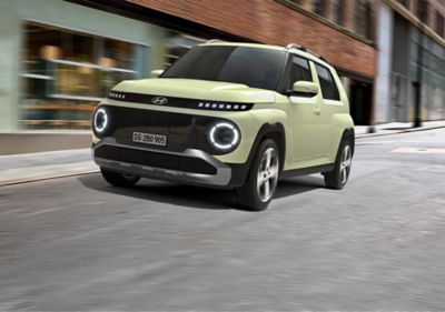 Ein Mann sitzt auf dem Fahrersitz des neuen Hyundai INSTER, eines kleinen Elektroautos.