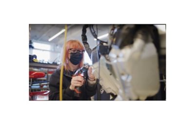 En dame jobber med montering av robot. Foto.