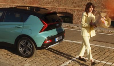 Hyundai BAYON parcheggiato su una strada cittadina visto da dietro.