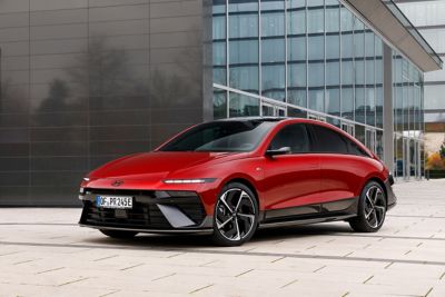 Driekwart vooraanzicht Hyundai IONIQ 6 geparkeerd voor een modern gebouw.