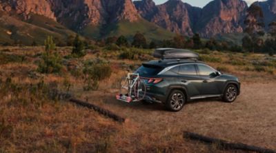 TUCSON Plug-in v přírodě s nosičem kol a střešním boxem.