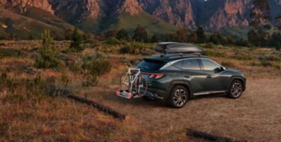 TUCSON Plug-in v přírodě s nosičem kol a střešním boxem.