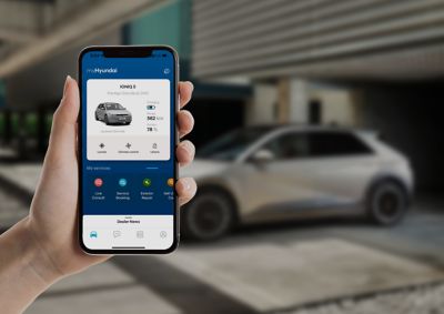 Smartphone in een hand met op het scherm de Hyundai IONIQ 5 in de Bluelink-app.