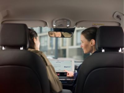 A woman inside her Hyundai updating the Bluelink map & infotainment software.