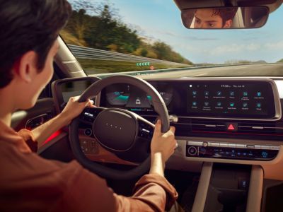 Innenraum eines Hyundai IONIQ 6 mit Lenkrad, Head-up-Display und Bedienelementen. 