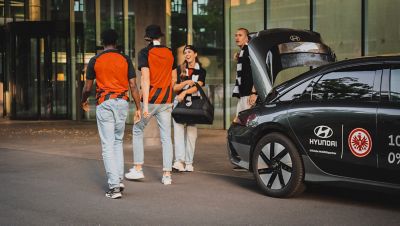 Eintracht Fans bei der Ankunft am Stadion am Heck des Hyundai IONIQ 6