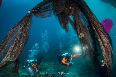 Dos buzos de Ghost Divers recuperando redes de pesca desechadas bajo el agua para su reciclaje.
