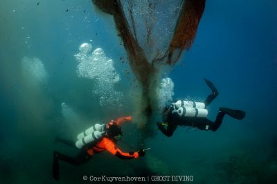 Zwei Taucher bergen alte Kunststoff-Fischernetze aus dem Meer. 