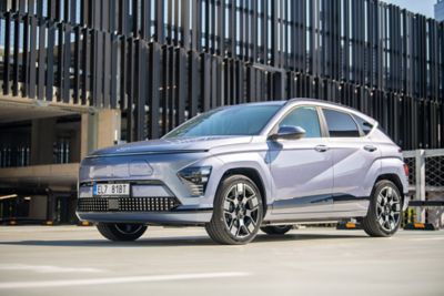 Žena se opírá o zaparkovaný vůz Hyundai KONA Electric ve městě.