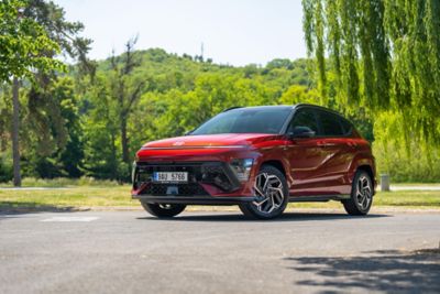 The all-new KONA N Line in red parked next to a modern building.