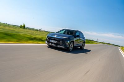 Hyundai Kona jedoucí po silnici krajinou.