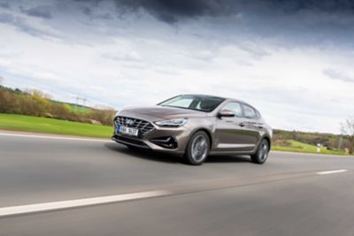 Předoboční pohled na model hyundai i30 Fastback na okresní silnici.