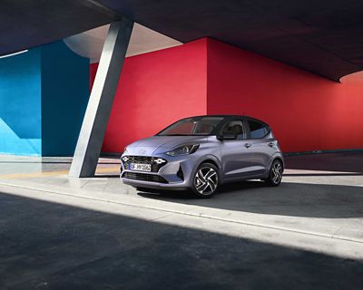 Hyundai i10 est garée devant un mur rouge et bleu.