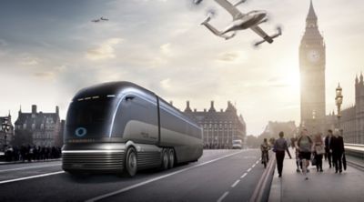 Ein futuristischer Bus mit Hyundai Emblem auf einer innerstädtischen Straße, darüber eine bemannte Drohne.