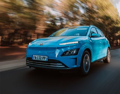 Hyundai KONA Electric na snímku zepředu při jízdě po venkovské silnici.