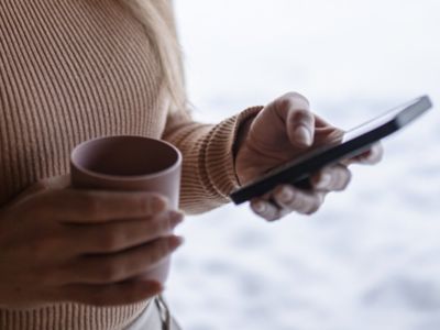 Woman holding coffee and phone.