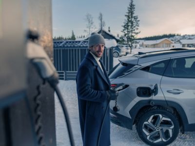 Man charging his Hyundai in the snow.