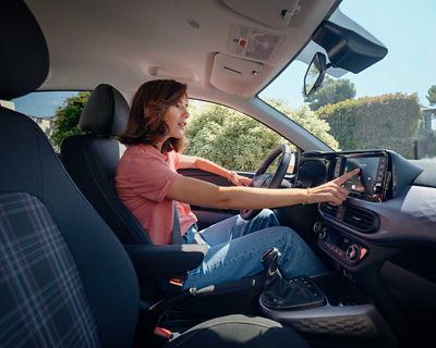 Une femme dans la nouvelle Hyundai i10 utilisant l'écran tactile.