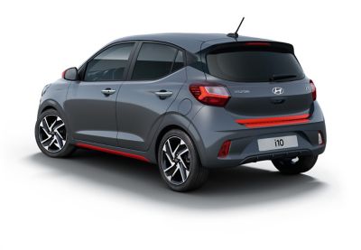 De nieuwe Hyundai i10 in het zwart met een rode sierstrip op de achterklep en een sierstrip achteraan in Tomato Red.