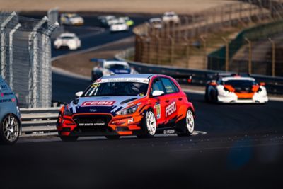  A picture of Hyundai Motorsport’s i30 N TCR in action on a racetrack shown from the front.