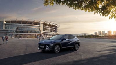 Hyundai KONA modrej farby stojaci v 3/4 pohľade pred futbalovým štadiónom FIFA