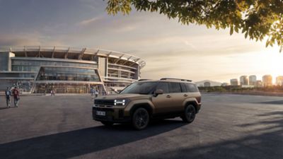Hyundai TUCSON bielej farby stojaci v 3/4 pohľade pred futbalovým štadiónom FIFA