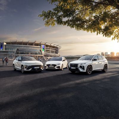 Drei Hyundai N Line Modelle in weißer Außenfrabe stehen im Halbkreis geparkt vor einem Stadion