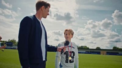    Ein Mann, der auf dem Spielfeld ein junges Fußballtalent interviewt