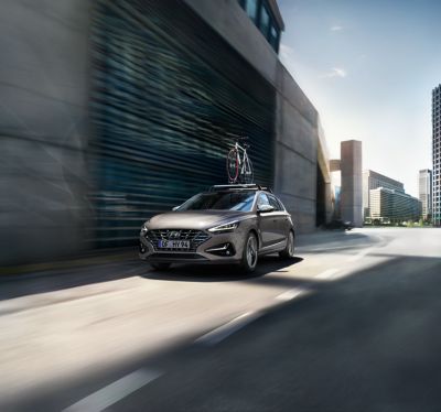 The Hyundai i30 with the bike carrier driving on a city road.