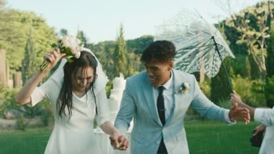 Due ragazzi al loro matrimonio corrono sotto la pioggia