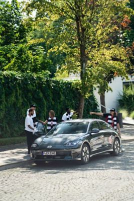 Eintracht Fans vor einem Hyundai IONIQ 6.