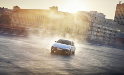 Der Hyundai IONIQ 6 N driftet durch die Straßen der Stadt mit einer Skyline im Hintergrund.