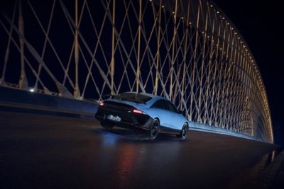Der vollelektrische Hyundai IONIQ 6 N beim Cruisen durch abendliche Straßen mit beleuchteten LED-Scheinwerfern.