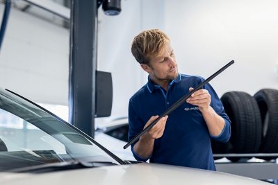 Eine Hyundai Servicemitarbeiter wirft einen prüfenden Blick auf die Wischblätter eines Hyundai.